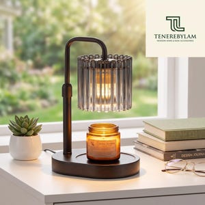 May include: A dark brown metal candle warmer lamp with a cylindrical fluted glass shade. The lamp sits on an oval base next to a glass jar candle labeled Aroma Sensation. The lamp emits a warm glow, illuminating the candle and the surrounding area.