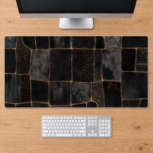 May include: A rectangular desk mat featuring a black and dark gray mosaic pattern of irregular rectangular shapes. The segments are separated by thin, metallic gold lines, with some sections displaying textured, speckled, or cracked details.