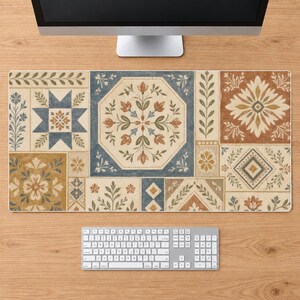 May include: A rectangular desk mat featuring a patchwork design of various square and octagonal tiles. The pattern includes floral motifs, geometric stars, and leaf sprigs in shades of muted blue, terracotta, mustard yellow, and cream on a light background.