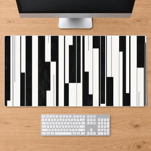 May include: A rectangular desk mat featuring a high-contrast pattern of vertical black and white stripes of varying widths. The design consists of solid black blocks and white spaces arranged in an irregular, linear sequence across the entire surface.