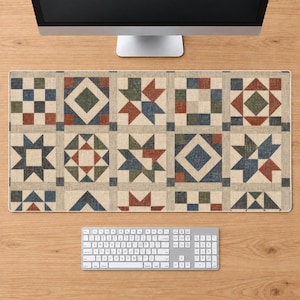 Puede incluir: Una alfombrilla de escritorio rectangular con un patrón de cuadrícula repetitivo de bloques de edredón geométricos en tonos apagados de rojo, azul, verde y beige. El diseño consta de varias formas de estrellas y diamantes.