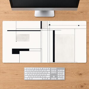 May include: A rectangular desk mat featuring a white background with a geometric pattern of thin black lines, solid black rectangles, and light gray rectangular blocks. The design is composed of intersecting horizontal and vertical lines.