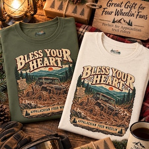 May include: An olive green and a cream-coloured t-shirt, each featuring a graphic of an off-road vehicle in mud with the text "BLESS YOUR HEART" and "APPALACHIAN FOUR WHEELIN'" above and below the scene, plus a sign reading "SOME HOLES JUST HIT DIFFERENT."