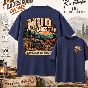 Könnte beinhalten: Ein kurzärmeliges T-Shirt in Marineblau mit einem großen Grafikdruck auf der Rückseite, der ein Geländefahrzeug im Schlamm vor einer Berg- und Waldkulisse zeigt, ergänzt durch den Text Mud Looks Good On Me und Appalachian Four Wheelin'.