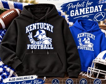 May include: A black hooded sweatshirt and a royal blue hooded sweatshirt, both featuring a white graphic of a person wearing a baseball cap and making a peace sign, with the text KENTUCKY FOOTBALL printed in white block lettering.