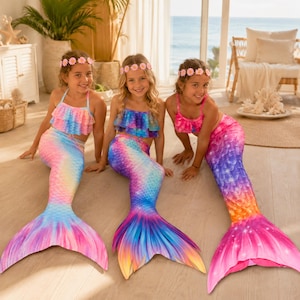 Può includere: Tre costumi da sirena con motivi a scaglie iridescenti nei toni del rosa, blu, viola e arancione. Ogni set include un top bikini con volant e una lunga coda fluida con pinna, completati da una fascia per capelli floreale abbinata.