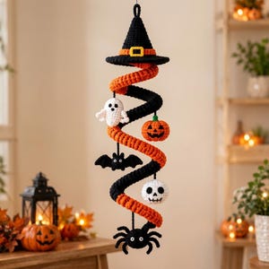 May include: A hanging crochet Halloween decoration featuring a black witch hat at the top, followed by a spiral of alternating orange and black yarn. Attached to the spiral are small crocheted figures: a white ghost, orange pumpkin, black bat, white skull, and a black spider.