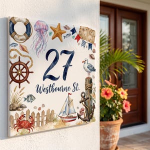 以下が含まれることがあります： 数字の27とWestbourne St.という文字が書かれた正方形の番地プレート。浮き輪、クラゲ、ヒトデ、舵輪、カモメ、ヨット、錨、砂浜にいる赤いカニといった航海をテーマにしたイラストが描かれています。