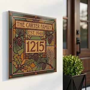 Peut inclure: Une plaque de maison carrée avec un motif de style vitrail portant le texte THE CARTER FAMILY, EST. 1948 et le numéro 1215. Le graphisme comprend des illustrations de pommes de pin, de feuilles de chêne et de blé dans des tons marron, vert et beige.