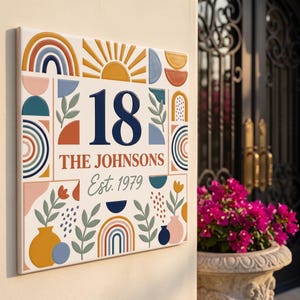 Puede incluir: Un letrero cuadrado de número de casa con el número 18, el texto THE JOHNSONS y Est. 1979. El diseño incluye formas geométricas coloridas, arcoíris, soles y motivos florales en tonos azul, naranja, amarillo, rosa y verde sobre blanco.