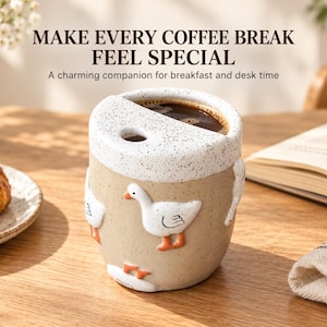 May include: A ceramic mug with a speckled beige body and a white speckled rim, featuring raised white goose figures with orange feet. The mug has a semi-circular opening at the top and contains dark coffee. Text reads: MAKE EVERY COFFEE BREAK FEEL SPECIAL.