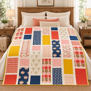 May include: A rectangular quilt featuring a patchwork design of vertical columns with various patterns including red flowers, yellow blocks, blue geometric shapes, pink hexagons, and stylized cat faces on a cream background with stitched texture.