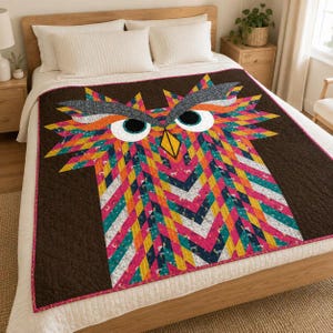 May include: A quilt featuring a large, stylized owl face composed of geometric, multi-colored fabric strips in shades of pink, orange, yellow, teal, and white. The owl has prominent white circular eyes with black pupils and a yellow triangular beak.