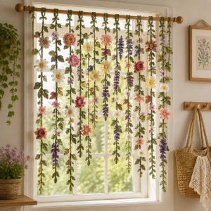 May include: A window curtain featuring multiple hanging strands of crocheted green vines adorned with various colorful flowers including pink roses, white daisies, and purple lupines. The strands are suspended from a wooden rod across the window frame.