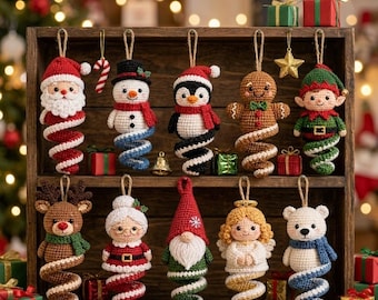 May include: A collection of ten crocheted Christmas ornaments hanging in a wooden crate. The figures include Santa, a snowman, a penguin, a gingerbread person, an elf, a reindeer, Mrs. Claus, a gnome, an angel, and a polar bear, each with a spiral base.