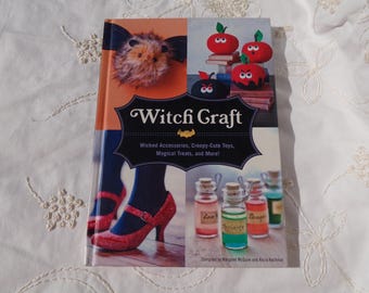 May include: A book titled "Witch Graft" with a colorful cover featuring a witch's hat, red and black apples, and a pair of red shoes. The book's subtitle reads "Wicked Accessories, Creepy-Cute Toys, Magical Treats, and More!"
