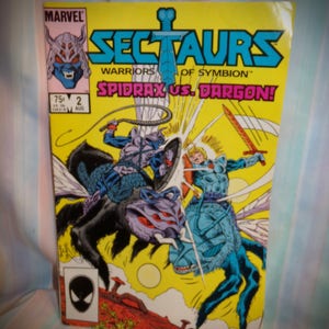 May include: A Marvel Comics comic book cover featuring the title "SECTAUURS: WARRIORS OF SYMBIOT" and the subtitle "SPIDRAX VS. DARGON!" The cover art depicts two characters riding insectoid creatures, one in blue and one in black, battling with swords and whips. The comic book is issue number 2 and is dated August.
