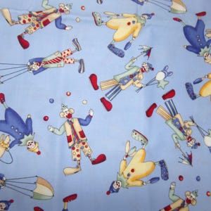 May include: A light blue fabric featuring a repeating pattern of clowns in various poses. The clowns wear colorful outfits including yellow, blue, and red garments, some holding umbrellas, balloons, or juggling balls against the solid blue background.