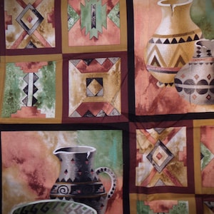 May include: A patchwork fabric with a southwestern design featuring brown, green, and red geometric patterns. The fabric also features a painting of two brown and black pottery jugs with geometric designs.