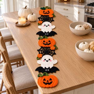 Peut inclure: Un long chemin de table crocheté pour Halloween présentant un motif répétitif de citrouilles orange, de toiles d'araignée noires, de fantômes blancs aux joues roses et de chauves-souris noires, agrémenté de petites fleurs orange et feuilles vertes.