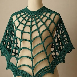 Può includere: Un poncho all'uncinetto verde scuro caratterizzato da un motivo a ragnatela traforato. Il capo presenta uno scollo rotondo e un orlo a punta, realizzato con filato spesso in un disegno geometrico a rete che ricade sulle spalle.