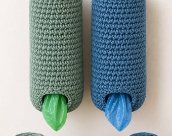 May include: Two cylindrical crochet bag dispensers, one sage green and one blue, each featuring a circular top handle. A green plastic bag protrudes from the sage dispenser, while a blue plastic bag extends from the blue one. Two yarn balls and a bowl of beads sit below.