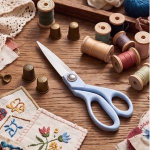 May include: A pair of light blue sewing scissors with silver blades and a decorative metal pivot screw, surrounded by several wooden spools of coloured thread, four brass thimbles, and pieces of white fabric featuring floral embroidery.