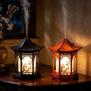 Puede incluir: Dos difusores de aceites esenciales con forma de pagoda, uno negro y otro marrón rojizo, que emiten un chorro vertical de vapor. Los difusores cuentan con centros cilíndricos iluminados decorados con un delicado patrón de flores de cerezo.