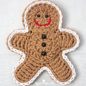 May include: A crocheted gingerbread man in brown with white edging and a red smile. It has black button eyes and three black buttons. The text "Repeat Crafter Me" is visible in the bottom right corner. A festive, handmade item.