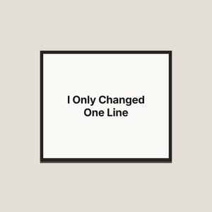 Puede incluir: Una pieza de arte mural rectangular con un marco negro fino que rodea un fondo blanco. Centrado en la superficie blanca, el texto negro "I Only Changed One Line" está escrito en una fuente sans-serif clara en dos líneas distintas.