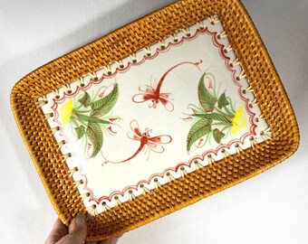May include: Rectangular serving tray with a woven rattan border. The center features a white ceramic surface with red dragonflies and green and yellow floral accents. The tray is designed for serving food or displaying items.