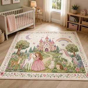 May include: A rectangular area rug featuring a whimsical illustration of a princess in a pink dress, two unicorns, a deer, a rabbit, and a hedgehog. The scene includes a castle, a rainbow, a crescent moon, and trees, all framed by a floral border.