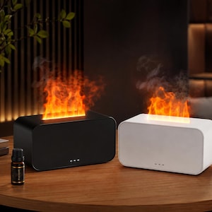 Peut inclure: Deux diffuseurs d'arômes rectangulaires, l'un noir et l'autre blanc, chacun doté d'une fente supérieure émettant un effet de flamme orange simulé avec de la brume. Un petit flacon d'huile essentielle en verre brun est posé à côté du diffuseur noir.