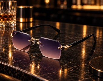 May include: Rimless sunglasses featuring rectangular gradient lenses that transition from a dark purple to a light amber hue. The frame includes gold-toned metal bridge and hinge accents, paired with sleek black temples for a refined appearance.