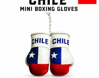 May include: A pair of mini boxing gloves featuring the Chilean flag design with white, blue, and red colors. The word CHILE is printed in blue on the white cuff of each glove. A white braided cord connects the two gloves at the top.