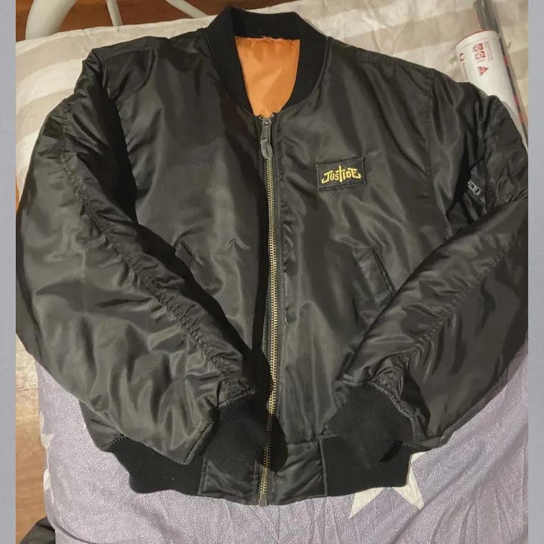 Back view of a vintage Justice Cross satin varsity jacket featuring embroidered streetwear detailing and a classic unisex bomber design. The jacket combines a smooth satin finish with a relaxed varsity silhouette, making it a versatile statement piece for casual outfits, urban fashion, retro-inspired styling, everyday wear, and streetwear looks.
