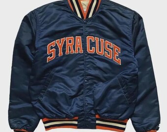 Puede incluir: Una chaqueta universitaria de satén azul marino con la palabra SYRACUSE bordada en naranja en el pecho. La chaqueta cuenta con cierre de botones a presión, dos bolsillos laterales y puños y dobladillo acanalados con rayas naranjas, blancas y azul marino.