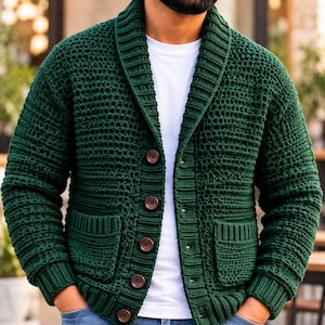May include: A dark forest green knit cardigan featuring a shawl collar, long sleeves with ribbed cuffs, and a button-down front closure. The garment has two front patch pockets and a textured stitch pattern, worn over a plain white t-shirt.