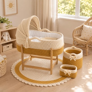May include: A cream and mustard yellow crocheted bassinet with a matching hood, resting on a wooden stand. The set includes a round crocheted rug, a tall storage basket, and a small rectangular basket, each featuring a decorative crocheted bow.