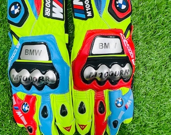 Puede incluir: Un par de guantes de motocicleta con un esquema de colores amarillo neón, rojo y azul con la marca BMW y M1000RR. Los guantes incluyen protectores de nudillos, logotipos circulares de BMW y detalles en tono plateado en el dorso.
