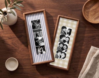 Puede incluir: Dos marcos rectangulares de madera que contienen tiras verticales de fotografías en blanco y negro. Un marco presenta un fondo de rayas azules y blancas, mientras que el otro muestra un patrón de cuadros beige y blanco detrás de la tira.