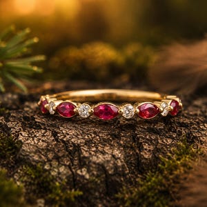 Peut inclure: Une bague en or jaune composée d'une alternance de rubis rouges taille marquise et de diamants blancs taille ronde. Les pierres précieuses sont serties en une rangée continue sur la moitié supérieure de l'anneau en métal poli et brillant.