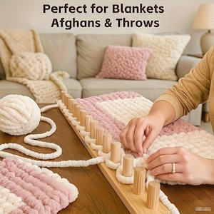 Könnte beinhalten: Ein rechteckiger Strickrahmen aus Holz mit vertikalen Stiften, der für die Arbeit mit dickem, weichem Garn in Creme und Altrosa verwendet wird. Der Text "Perfect for Blankets Afghans & Throws" ist oben im Bild zu sehen.