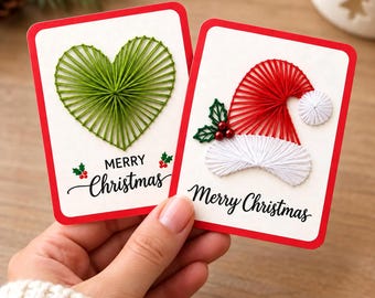Puede incluir: Dos tarjetas rectangulares blancas con bordes rojos y diseños de arte con hilos. Una tarjeta muestra un corazón verde y el texto Merry Christmas con acebo. La otra tarjeta muestra un gorro de Papá Noel rojo y blanco y el texto Merry Christmas.