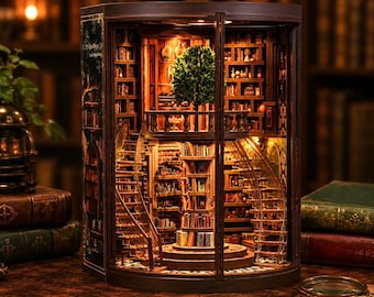 Puede incluir: Un diorama de madera para estantería que muestra una biblioteca de varios niveles con un árbol central, escaleras de caracol y estantes iluminados llenos de libros diminutos, encerrado en un marco oscuro con luz cálida.