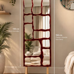 May include: A rectangular floor mirror with a dark red, irregular grid frame. The mirror measures 50 cm in width and 130 cm in length, with a total height of 150 cm including the light-colored wooden legs. The frame creates multiple segments.