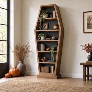 May include: A tall, coffin-shaped wooden bookshelf with a natural light brown finish and a dark charcoal interior back panel. The unit features six horizontal shelves holding various books, small potted plants, a skull, and a woven basket.