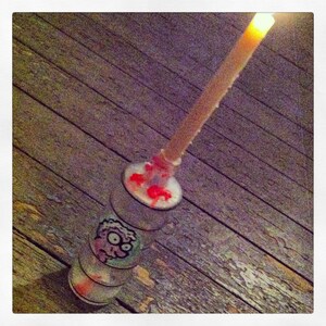 May include: A glass bottle with a red and white wax candle on top. The bottle has a cartoon character sticker on it.