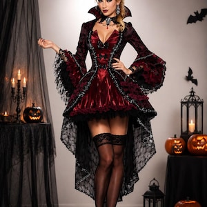 May include: A high-low dress in deep burgundy and black featuring long flared sleeves with lace trim, a structured collar, and a front bodice with decorative bows. The garment is paired with black lace-topped stockings and black high-heeled shoes.