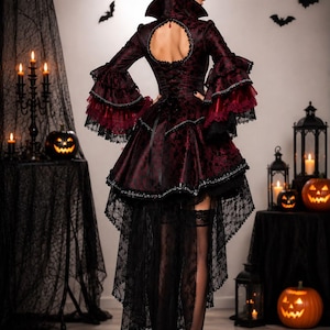 May include: A dark burgundy and black dress featuring a high collar, a circular back cutout, and layered bell sleeves with lace trim. The skirt has a high-low hemline with a long black lace train, paired with black stockings and high-heeled shoes.